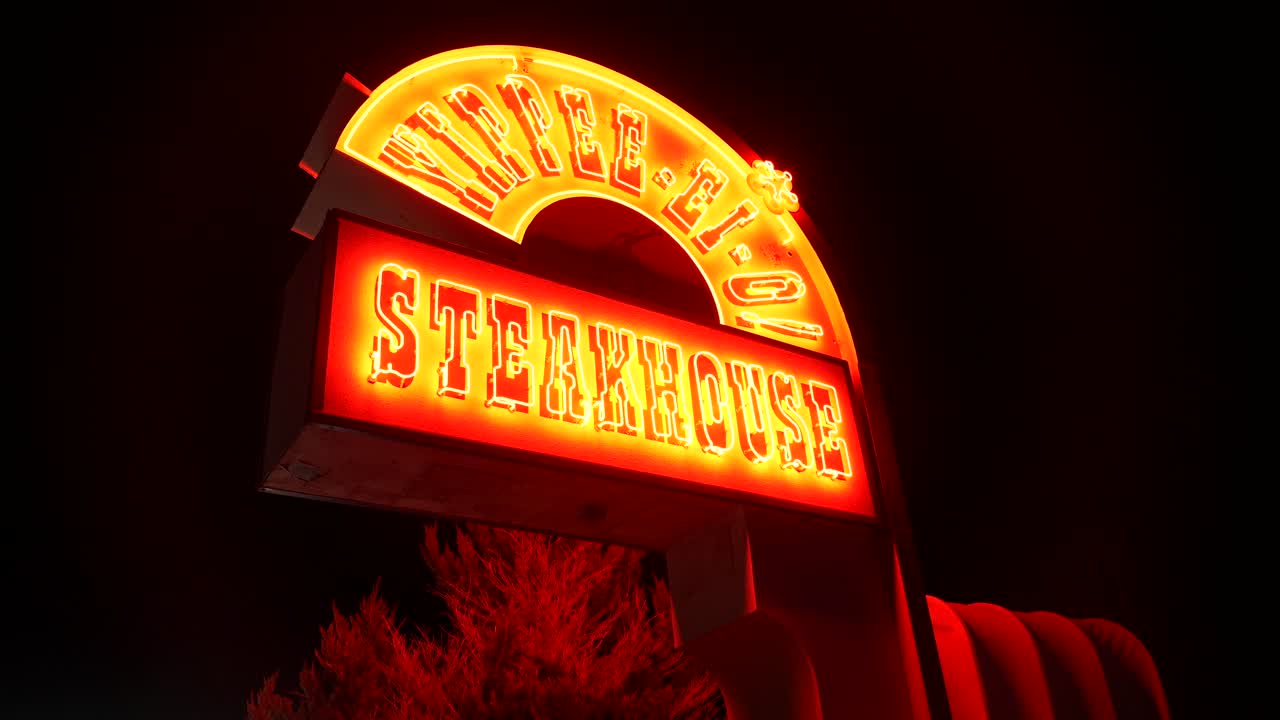 Zářivý neonový poutač pro steakhouse Yippee-Ki-Yay v noci