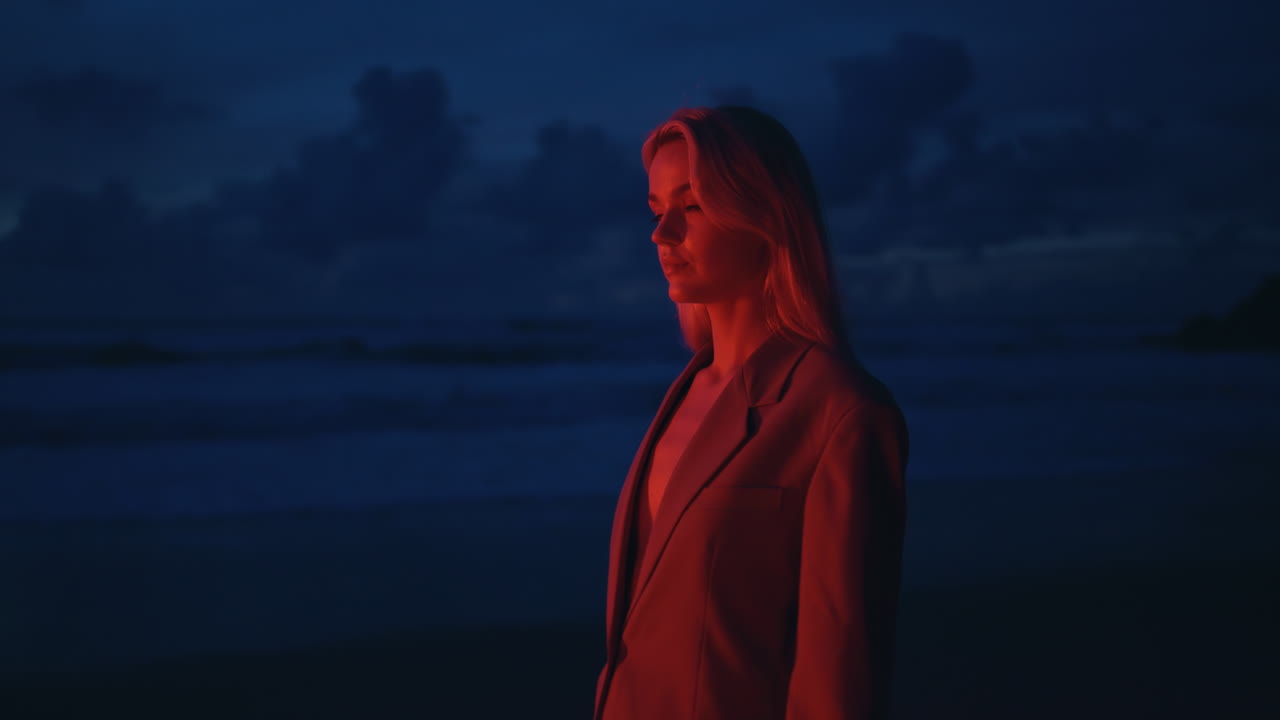 una chica seductora caminando por la costa en neón rojo por la noche.