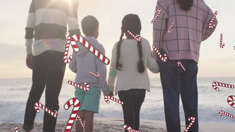 Animation-Von-Zuckerstangen-über-Einer-Gemischtrassigen-Familie-Am-Strand