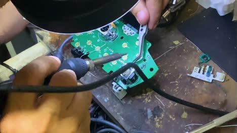 Technician soldering small metal filler in tiny circuit board with holders