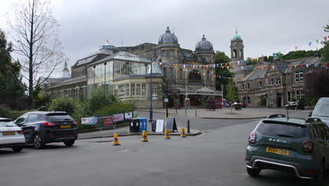 the buxton opera house in england, with its elegant domed towers and glass conservatory visible. colorful bunting decorates the area, adding a festive touch to the historic setting