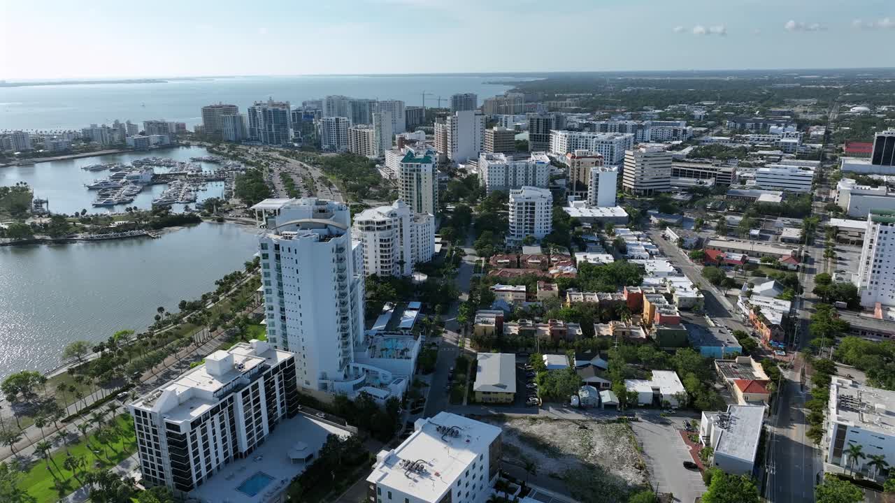 Sarasota Downtown with marina, luxury high-rise buildings and palm trees in summer. Gulf of America during sunny day in distance. Aerial wide shot. Coastline of Florida state.