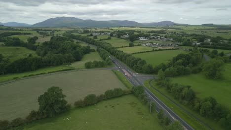 busy rural road a66 with mountain blencathra in the distance and green patchwork fields on overcast summer day