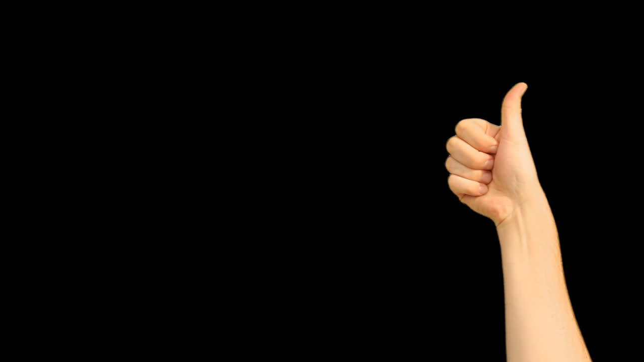 Human Hand Showing Thumbs Up Gesture on Black Background