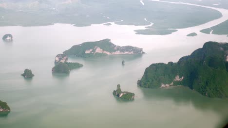 a view of the upper plane window while floating in the air, overlooking the mountains and natural water resources along the coast of thailand