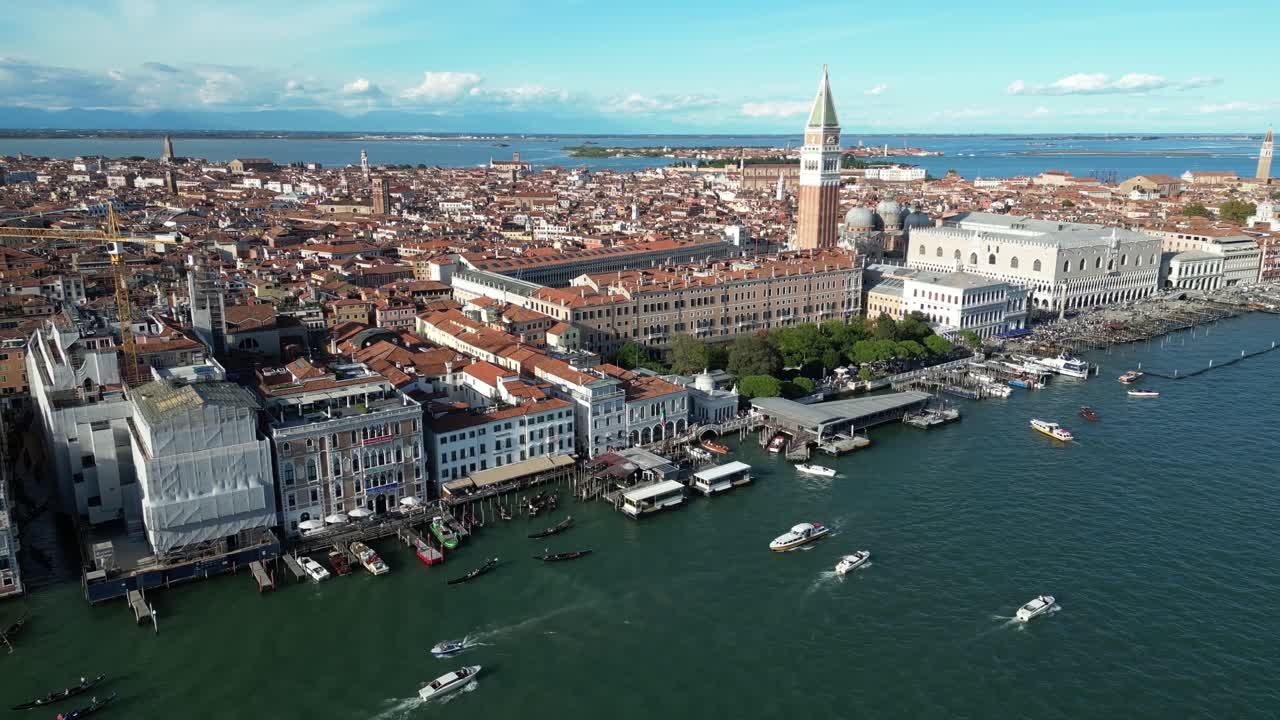 Drone view of Venice waterfront and St. Mark's Bell Tower with clear blue skies.