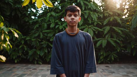 young man stands serenely in a courtyard, surrounded by vibrant green foliage, embracing the tranquility of nature as sunlight filters through the leaves