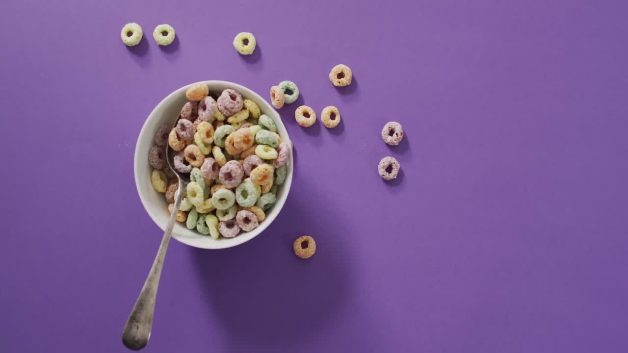 video de coloridos cereales de desayuno con tazón y cuchara sobre fondo púrpura