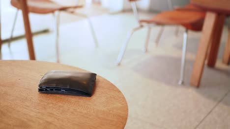 black wallet on wooden table in a cafe