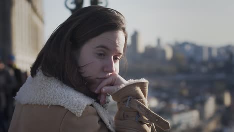 young woman hand on chin with sad face standing on opaque cityscape background in porto, portugal - slow motion