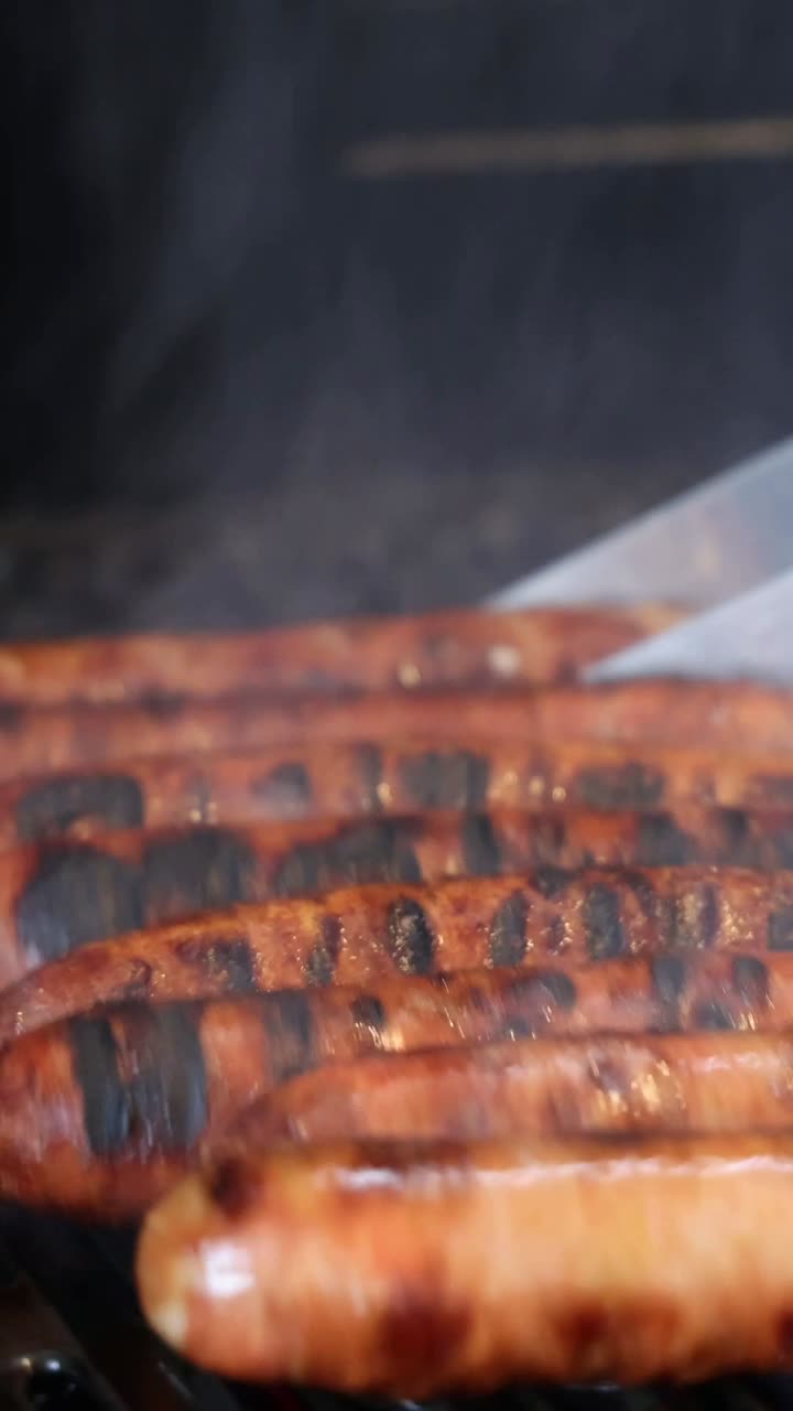 Sizzling sausages being turned on a hot grill