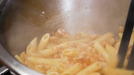 Mixing-steaming-hot-pasta-with-small-fresh-cooked-shrimps-in-close-up