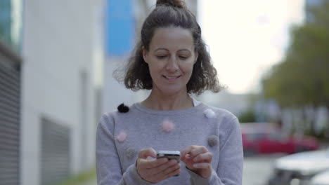 cheerful mature woman typing message on smartphone