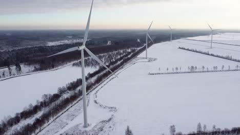 Vista-Aérea-De-Las-Palas-Giratorias-De-Las-Turbinas-Eólicas-En-El-Paisaje-Invernal-Cerca-Del-Bosque.