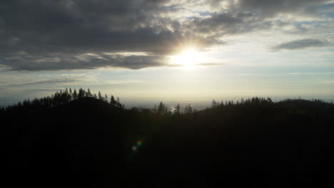 Aerial-flying-backwards-from-a-mountain-in-view-of-the-sunrise-and-the-river-that-runs-through-Redding,-CA