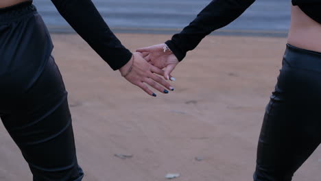 Two-women-dressed-in-black-holding-hands-next-to-the-road