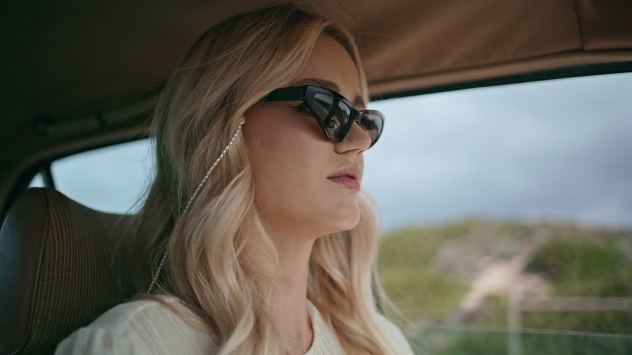 hermosa rubia conduciendo por la carretera con gafas de sol de cerca. conductor montando un automóvil.