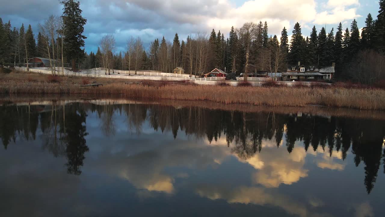 Scena sensazionale di splendidi riflessi del cielo nel lago Glimpse in Columbia Britannica, Canada, con una bella vista di un Home Ranch circondato da foreste di abeti.