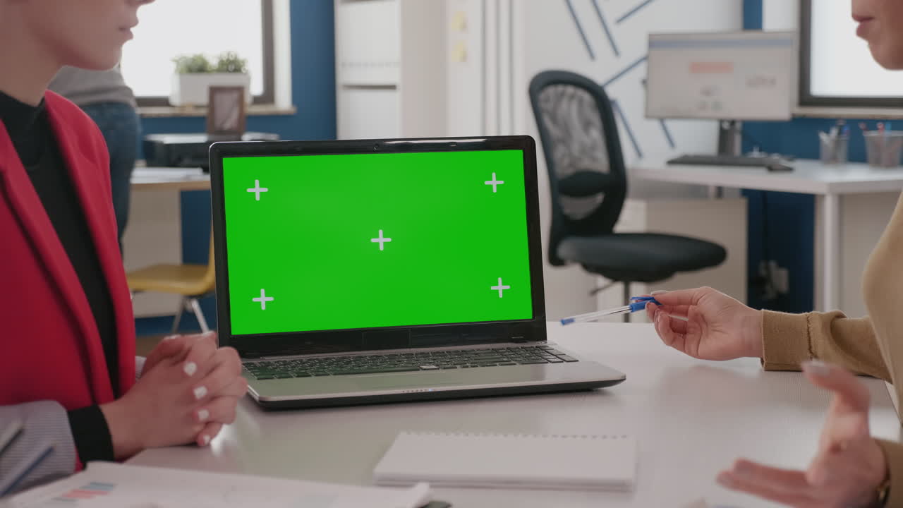 Close up of colleagues using laptop with green screen