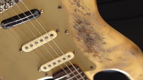 vieja guitarra eléctrica rayada sostenida por músico, vista de cerca