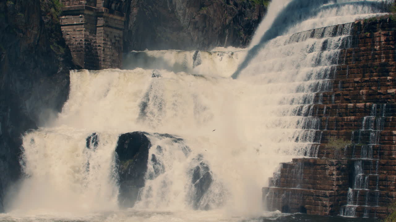 medium shot of bottom of new croton dam with powerful waterfall and stepped spillway leading down to the river. static, slow motion 40 fps
