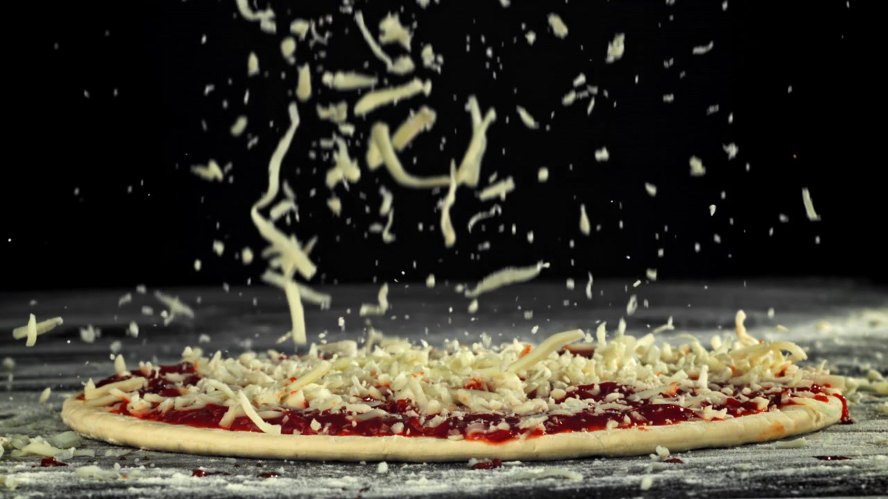 Rallentatore di mozzarella sfilacciata che cade sull'impasto della pizza.