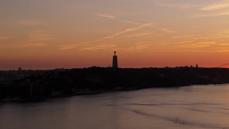 silhouette of national sanctuary of christ the king on tagus river at sunset