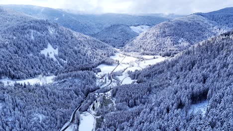 Drone-slow-fly-in-a-mountain-valley-covered-with-snow-during-springtime-with-blue-sky-and-big-clouds