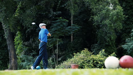 älterer-Asiatischer-Mann-Mit-Einem-Perfekten-Schwung,-Der-Auf-Dem-Grün-Des-Changi-Golf-Club-In-Singapur-In-Einer-Tropischen-Umgebung-Abschlägt