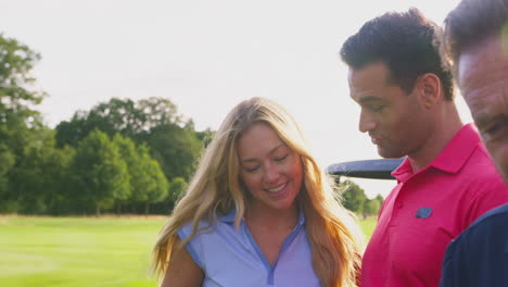 parejas maduras y adultas de pie junto al coche de golf comprobando las tarjetas de puntuación juntas