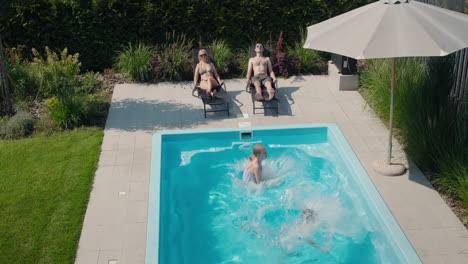 Children-jump-into-the-pool,-slow-motion-video.-Adults-rest-on-sun-loungers-nearby.