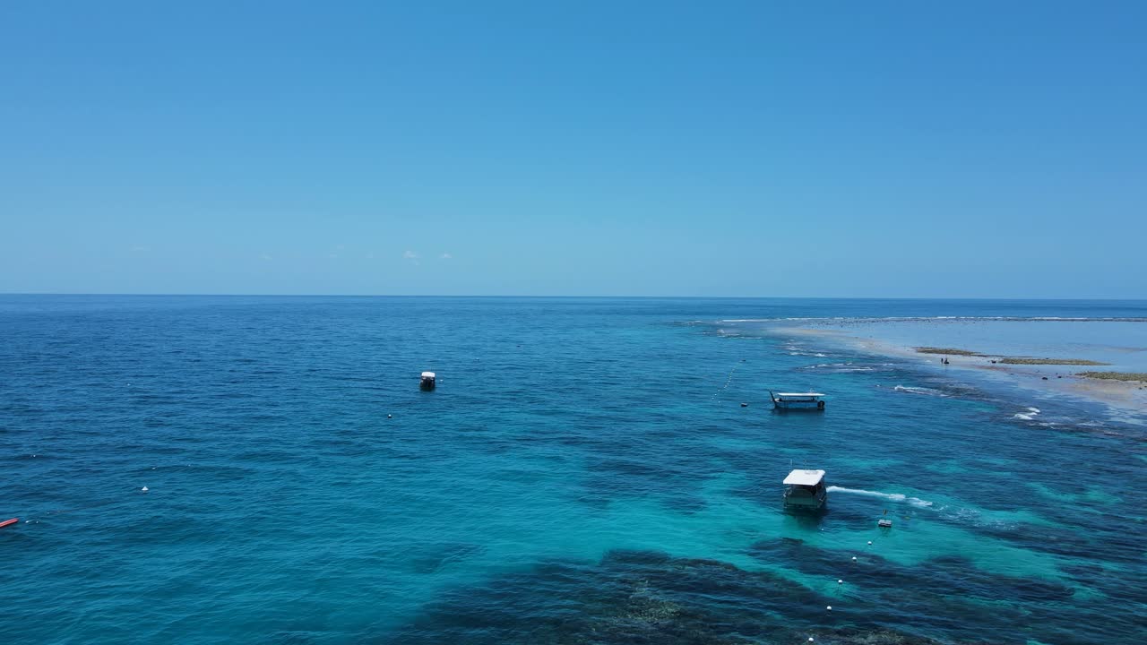 barcos de buceo flotando sobre un arrecife tropical en las aguas azules de una isla tropical