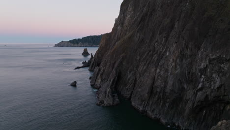 static aerial overview of the oregon coast with sea cliffs dropping in flakes into water, early morning dawn