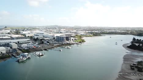 antena 4k, volando hacia adelante lentamente, vista de los suburbios de auckland y fábrica de barcos en la costa