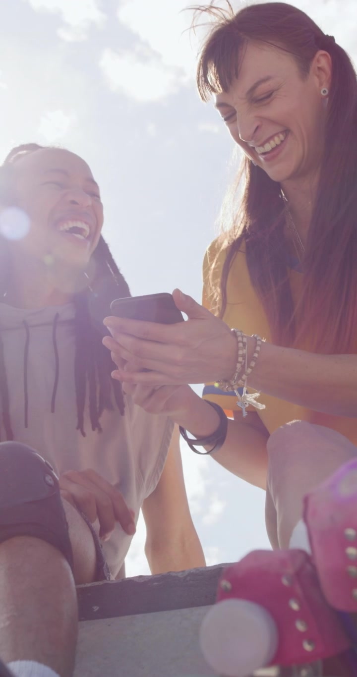 Pareja joven riendo y mirando el smartphone al aire libre
