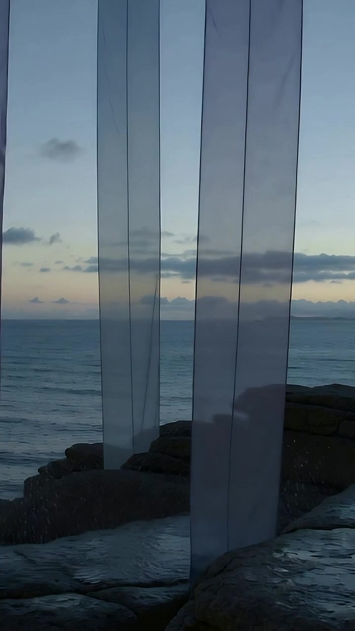 Vertical video: Moving from breeze, two sheer panels swinging in and out above rock ledge, dripping