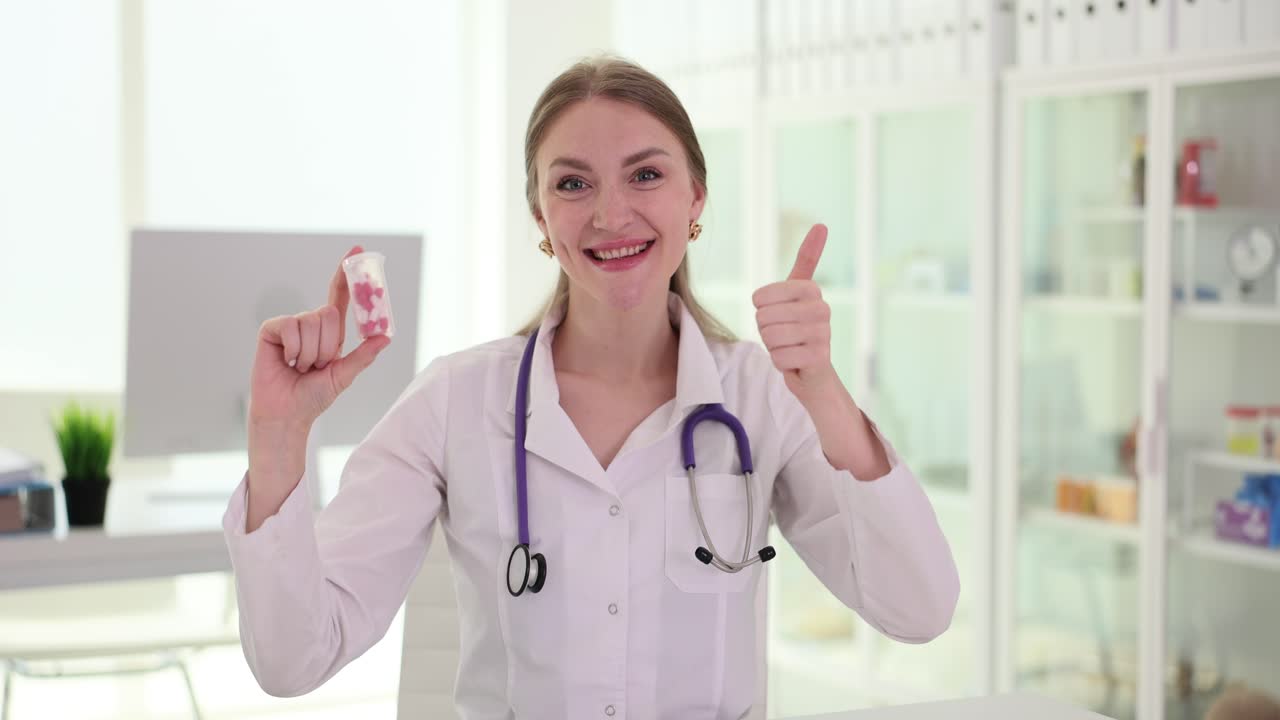 Female Doctor Holding Pills and Giving Thumbs Up in Clinic