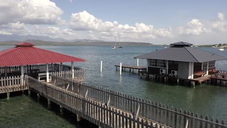 Flying-over-the-yawls-and-the-pier-towards-the-sea-a-beautiful-sunny-morning-in-Bahía-de-las-Calderas,-Bani-Dominican-Republic