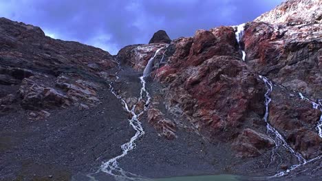 glacial alpine lake with waterfalls from rocks, aerial footage