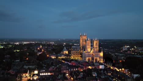 Ein-Luftdrohnenvideo-Fängt-Die-Berühmte-Lincoln-Cathedral-In-Lincolnshire,-Großbritannien,-In-Der-Abenddämmerung-Ein-Und-Präsentiert-Ihre-Majestätische-Gotische-Architektur-Mit-Beleuchtung