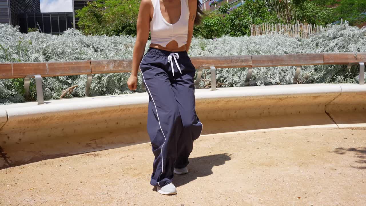 Young woman in track pants and tank top outdoors