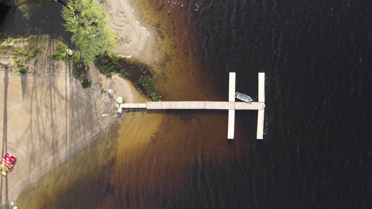 Vista aerea dall'alto di un molo con una singola barca e acqua bassa del lago a Restoule, Ontario, ascesa del drone