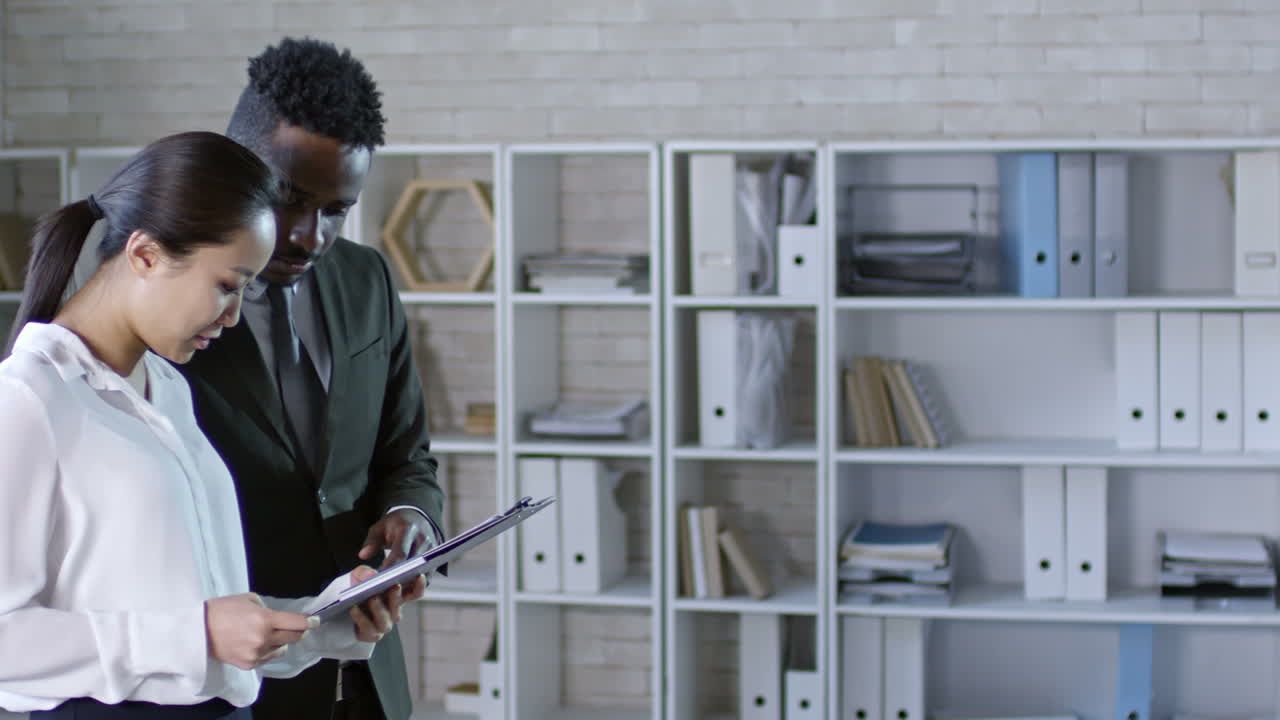 Medium Shot Of Young Bearded Businessman In Suit Approaching Two Colleagues And Shaking Hands With Them In Office
