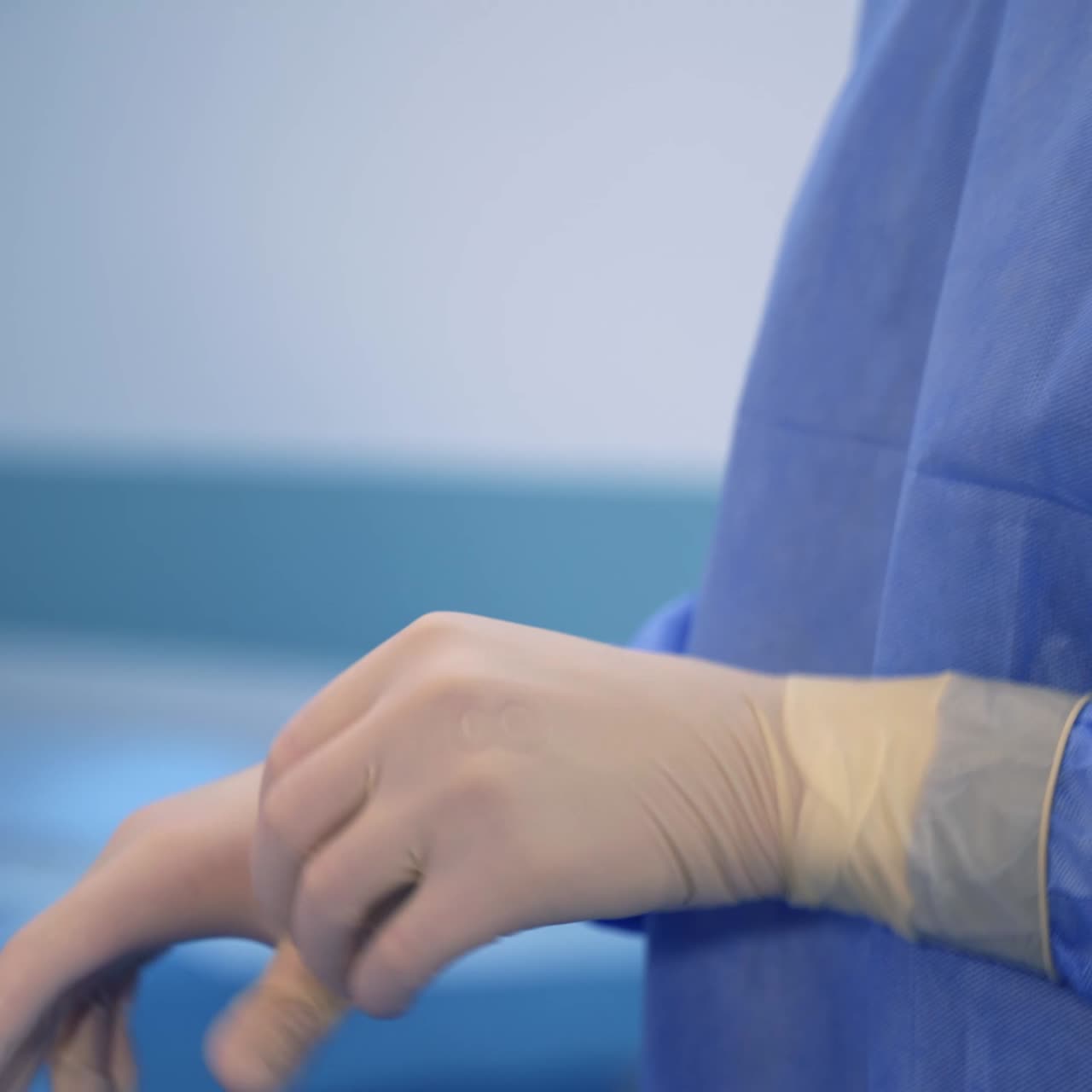 Surgery professional getting ready for operation. Doctor's hands putting on latex gloves and adjusting them tightly to the fingers. Close up