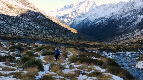 trekker hikes through remote snow covered mountain valley