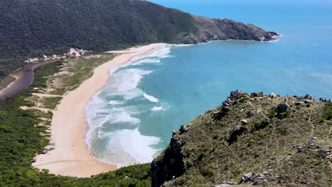 escena aérea de drones en montañas con playa desierta paraíso secreto con laguna de estuario que desemboca en el océano