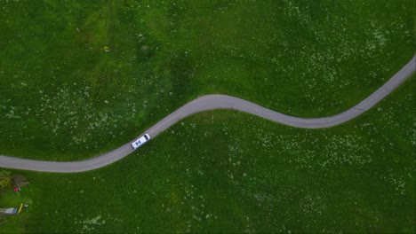 White-camper-van-driving-through-the-winding-mountain-road-around-the-alps,-Toblach,-Italy