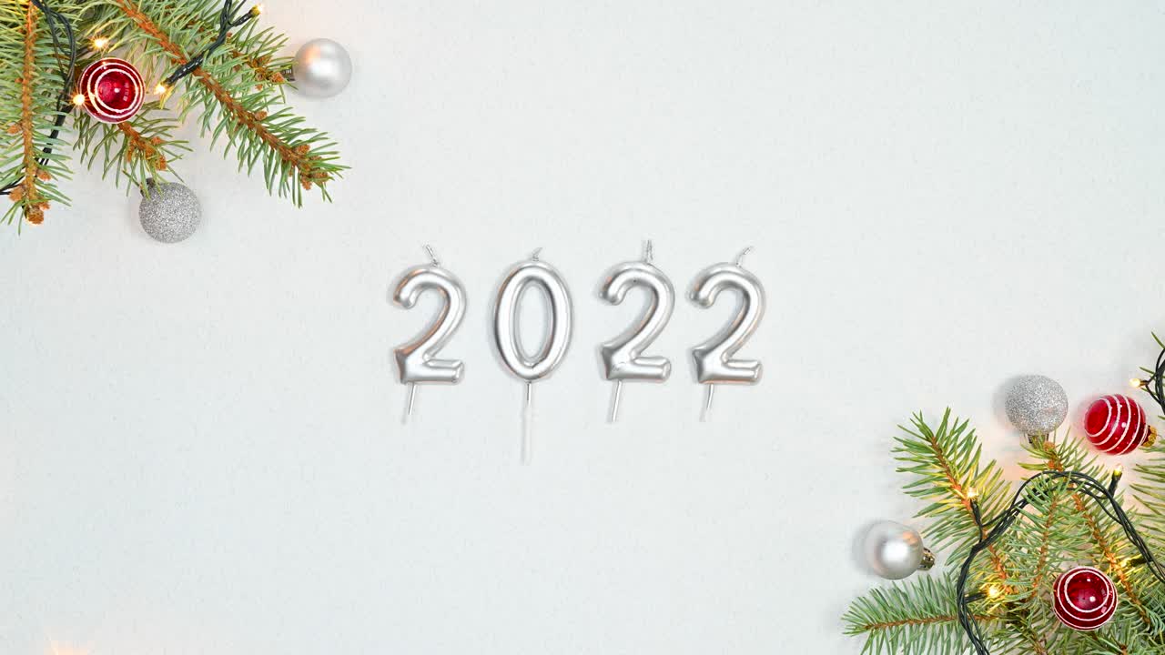 Luci intermittenti su composizione natalizia con ornamenti e numeri dell'anno 2022. Stop motion.