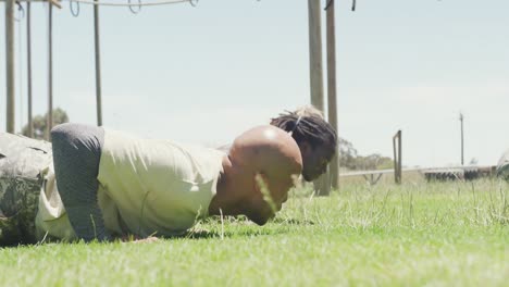 fit diverse group of soldiers doing press ups in field on army obstacle course in the sun