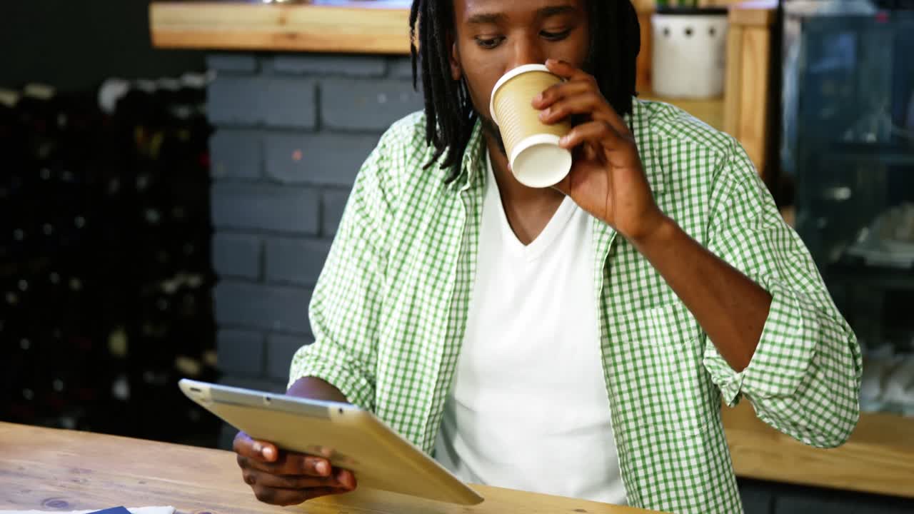 Uomo che utilizza la tavoletta digitale sorseggiando un caffè